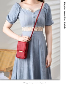 Detail of red leather crossbody phone bag featuring quilted pattern and gold buckle