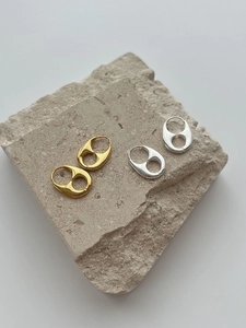 Detail of hollow geometric ear buckles in polished gold and silver finishes on stone