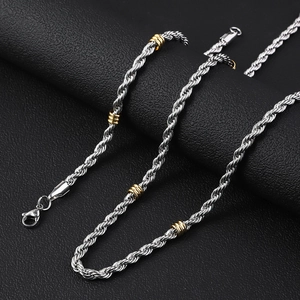 Silver stainless steel twist chain necklace with gold bead accents on black texture