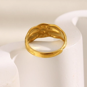 Close-up of gold plated stainless steel star ring on a white textured stone base