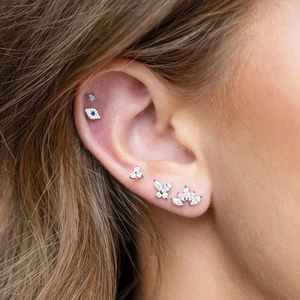 Detail of five 925 silver stud earrings with blue zircon on a model's ear