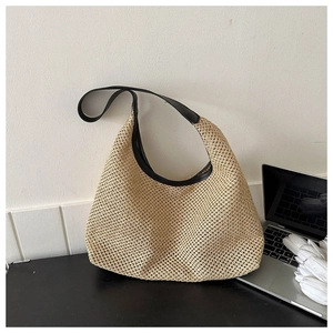 Close-up of woven straw tote bag with black leather shoulder strap detail