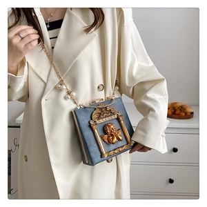 Close-up of vintage baroque handbag with embossed angel and gold chain strap
