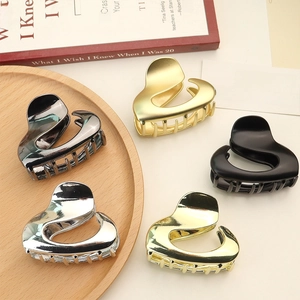 Sleek metallic claw clips in five finishes displayed on a minimalist wooden tray