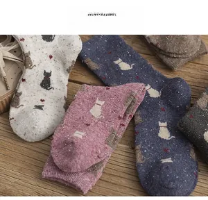 Close-up of knit wool socks featuring cute cat silhouettes and heart patterns on wood