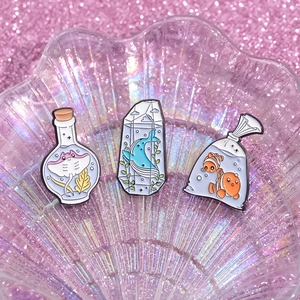 Three-piece set of cute cartoon marine animal enamel pins in a rainbow shell display tray