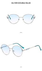 Detail of round silver metal frame sunglasses with blue gemstone accents and gradient lenses