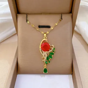 Peacock pendant necklace with red and green stones on a brown velvet jewelry box