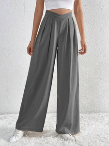 Detail of high-waisted dark grey wide-leg trousers with unique cross-waist pleated design
