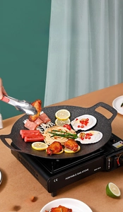 Detail of portable butane stove with non-stick maifan stone grill pan on a wooden table