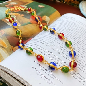 Detailed macro of vintage gold necklace with vibrant red, green, and blue beads