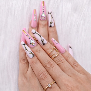 Detailed close-up of pink coffin press-on nails with marble design and rhinestones