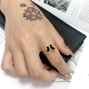 Close-up of a gold butterfly ring with a twisted band worn on a hand over a magazine