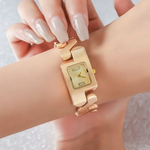 Detail of rose gold rectangular watch with minimalist dial and decorative chain bracelet
