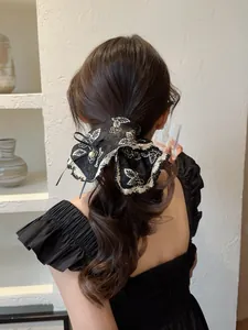 Detail of a vintage black lace scrunchie with floral embroidery and a pearl pendant