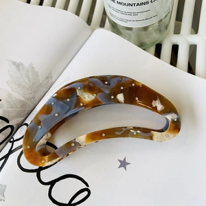 Detailed view of acetic acid hair claw clip with amber texture and sparkling rhinestones
