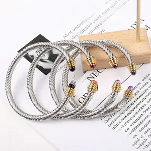 Macro detail of multi-colored gemstones on twisted cable bangles in stainless steel