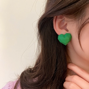 Close-up of green heart-shaped stud earring with matte finish worn by a model