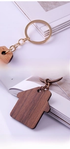 Macro detail of house-shaped walnut wood keychain with polished gold metal ring