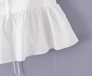Vue détaillée du tissu en coton blanc avec ourlet à volants et finitions de couture