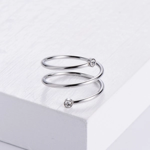 Minimalist silver spiral ring with sparkling zircons on a white geometric block