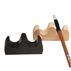 Minimalist wave-shaped calligraphy brush rests in black and wood finish on white background