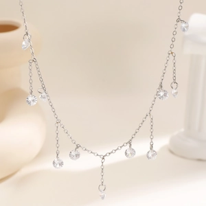 Elegante zilveren kwastjesketting met fonkelende kristallen hangers op een warme achtergrond