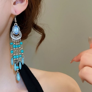 Detail of bohemian long tassel earrings with blue stones on silver metal hooks