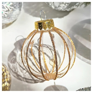 Close-up of transparent Christmas ball with vertical gold glitter stripes and metal cap