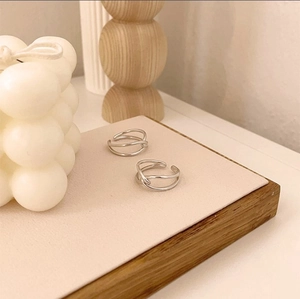 Detail of minimalist silver knot rings on a modern display stand with aesthetic decor