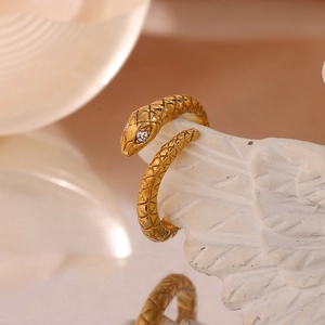 Macro detail of gold plated snake ring featuring lattice scales and sparkling white eyes