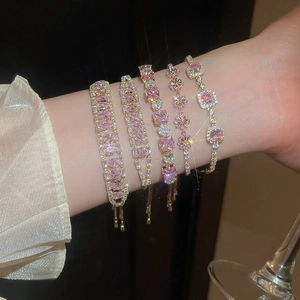 Close-up of gold bracelets with pink cubic zirconia and adjustable drawstring on wrist