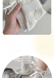 Detail of gray mid-calf cotton socks with white satin bows and textured floral patterns