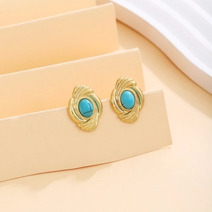 Close-up of vintage gold earrings with spiral texture and oval turquoise stones