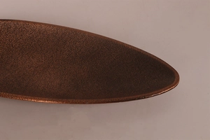 Close-up of a bronze incense tray showing detailed hammered texture and oval shape