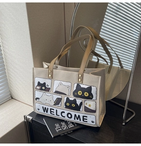 Detail of canvas tote bag with cat illustration, brown leather handles and mirror reflection