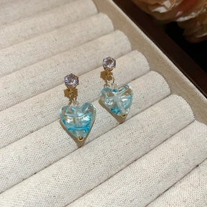 Detail of blue resin heart earrings with cubic zirconia studs on velvet jewelry box