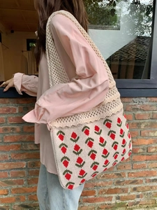 Detail of hand-knitted strawberry tote bag featuring crochet patterns and hollow out design