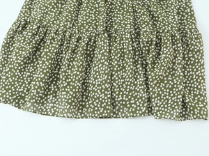 Détail de la robe vert olive à pois montrant l'ourlet à volants et le tissu fluide