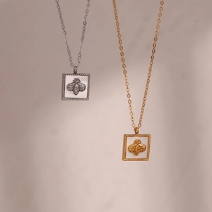 Macro detail of square bee pendants with white shell inlay in gold and silver finishes