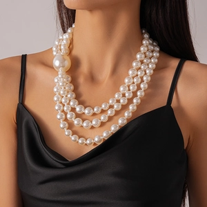 Detailed view of triple-layer pearl necklace with oversized pearl accent on neck