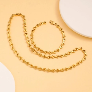 Ensemble collier et bracelet en acier inoxydable doré avec maillons en X sur fond chaud