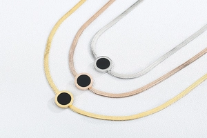 Flat snake bone necklaces in gold, rose gold and silver with black shell pendants