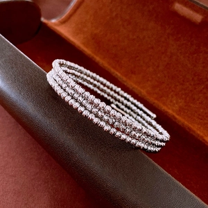 Close-up of triple-layered silver beaded bracelet with faceted texture on leather case