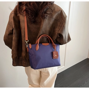 Detail view of purple nylon tote bag with brown straps worn on shoulder by a model
