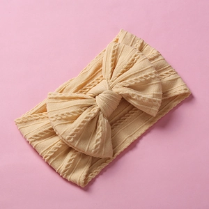 Close-up of beige baby nylon headband with knit texture and large soft bow detail