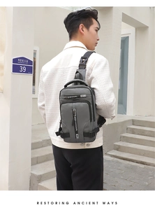 Outdoor shot of a man wearing a grey professional nylon crossbody bag with side buckle