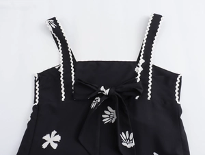 Detail von schwarzem Blumenkleid mit Wellensaum-Trägern und einer Schleife am Rücken