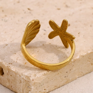 Starfish and seashell open ring in 18K gold plated stainless steel on a stone surface