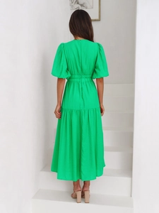 Detail of a bright green maxi dress featuring puff sleeves and a deep V-back design